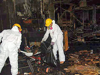 Fire damage cleanup crew removing debris from a damaged room